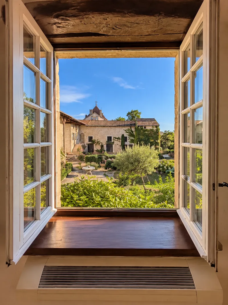 Vue depuis une fenêtre sur la cour, le jardin et la tour à girouette